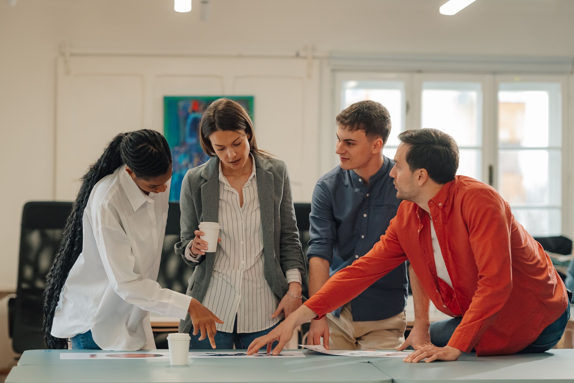 Marketing team analyzing charts and discussing strategy in modern office