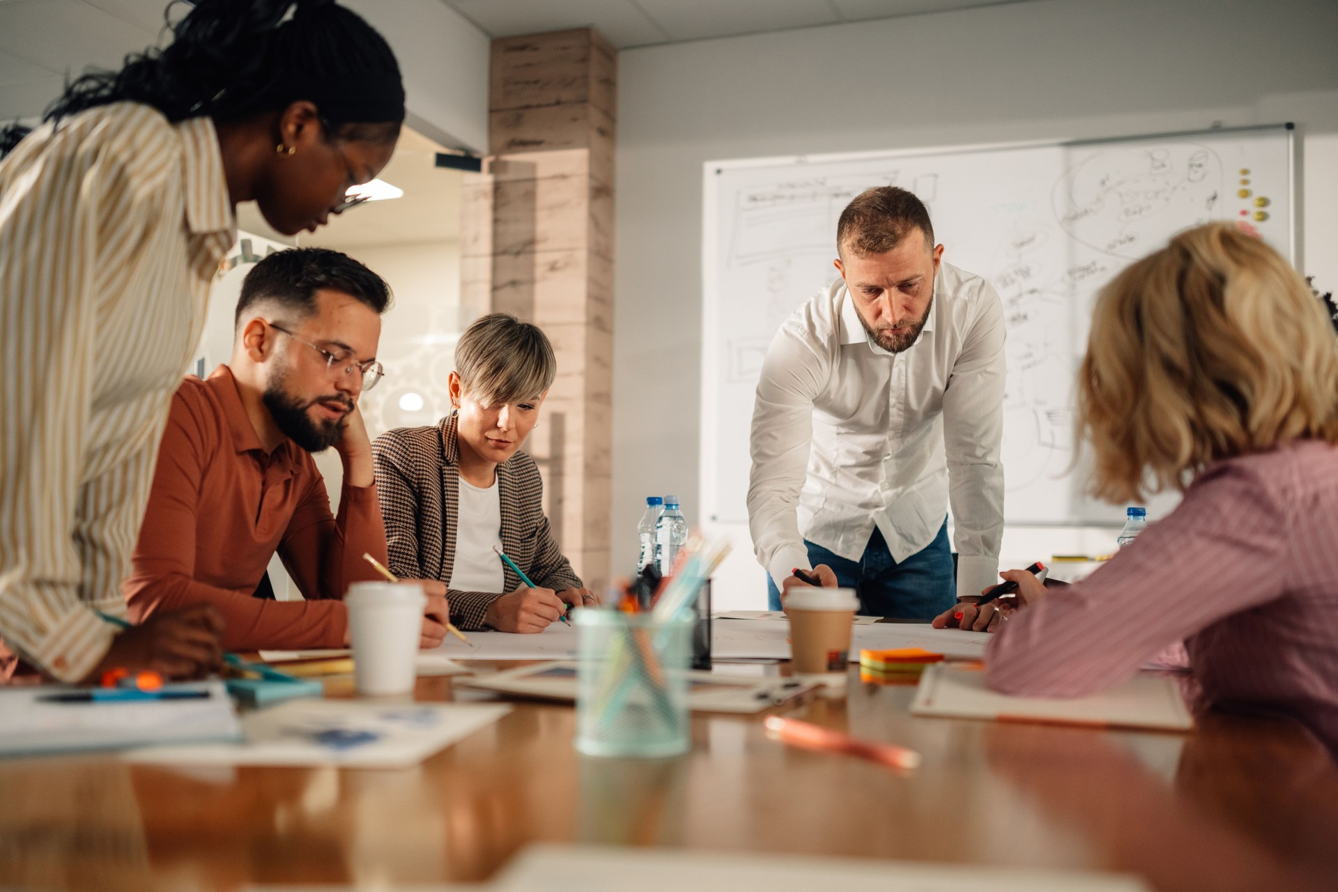 Diverse team collaborating on project, manager leading brainstorming session in modern office